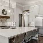 Open-concept kitchen in Mike DePriest’s Northlake, TX home, featuring a large kitchen island with seating, modern gray cabinets, and a spacious stainless steel fridge.